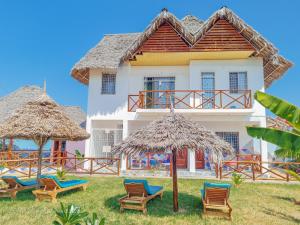 a house with chairs and umbrellas in front of it at Pineapple House in Nungwi