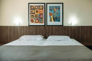 Una cama con dos almohadas y tres fotos encima. en Hotel Caverá, en Alegrete