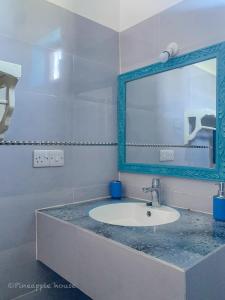 a bathroom with a sink and a mirror at Pineapple House in Nungwi