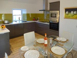 una cocina con una mesa de cristal con placas blancas. en Charlies Cottage, en Muasdale