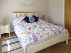 a bedroom with a bed with a floral bedspread at Charlies Cottage in Muasdale