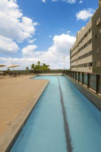 uma piscina de água azul ao lado de um edifício em Flat Beira Mar Boa Viagem- Beach Class Internacional no Recife