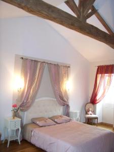 a bedroom with a white bed with pink curtains at La Genoise in Tillières