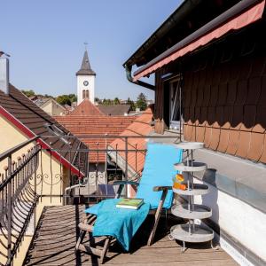 einen Tisch und einen Stuhl auf einem Balkon mit einem Uhrturm in der Unterkunft Charmante, großzügige Ferienwohnung Villa Fleurie in Bretten