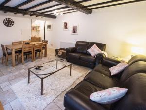 a living room with two leather couches and a table at Barbican Cottage in Middleham