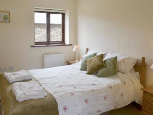 una camera da letto con un grande letto bianco con cuscini di Cider Barn a Poundstock