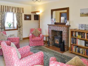 Hazels Cottage في Kilchenzie: غرفة معيشة مع كراسي حمراء ومدفأة