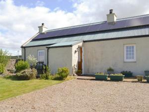 a white house with solar panels on the roof at Hazels Cottage in Kilchenzie