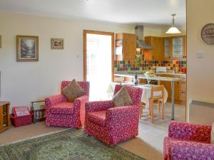 a living room with two chairs and a kitchen at Hazels Cottage in Kilchenzie