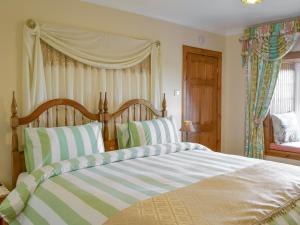 a bedroom with a large bed with striped pillows at Hazels Cottage in Kilchenzie