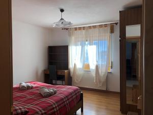 een slaapkamer met een bed, een bureau en een raam bij Appartamento Elisa in Taibon