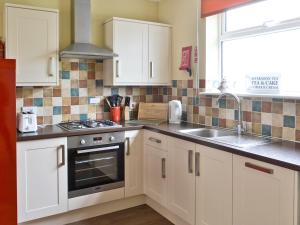 a kitchen with white cabinets and a sink at Stable Cottage - Ukc645 in Byrness