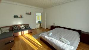 a bedroom with a white bed and a wooden floor at Kuckó Apartman in Badacsonytördemic