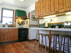 una cocina con armarios de madera y taburetes de bar en Dalvuie Beag, en Connel