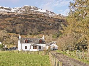 una casa blanca en un campo con una montaña en Dalvuie Beag, en Connel