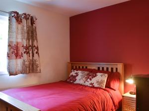 a bedroom with a bed with a red wall at The Ranch in Benmore