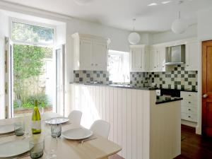 a kitchen with white cabinets and a table with wine glasses at Beech Hill in Burneside