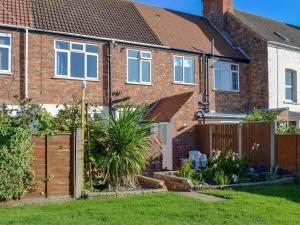 a house with a wooden fence in a yard at Shell Seekers Cottage in Hornsea