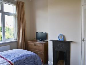 a bedroom with a bed and a television on a dresser at Shell Seekers Cottage in Hornsea