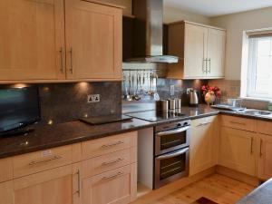 a kitchen with wooden cabinets and stainless steel appliances at The Old Butchers in Crantock