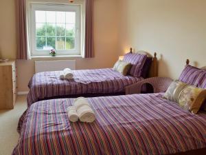 a bedroom with two beds and a window at The Old Butchers in Crantock