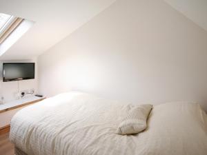 a white bedroom with a bed and a tv at Barn Cottage - E5560 in Winthorpe