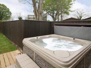 a hot tub in a backyard with a fence at Barn Cottage - E5560 in Winthorpe