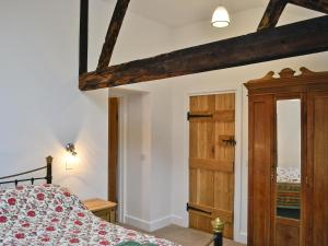 a bedroom with a bed and a wooden door at The Grooms Cottage in Ashperton