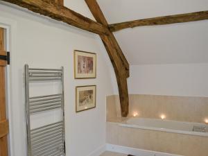 a bathroom with a bath tub and wooden beams at The Grooms Cottage in Ashperton