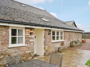 a stone house with two chairs in front of it at The Grooms Cottage in Ashperton