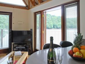 uma garrafa de vinho sentada numa mesa com uma taça de fruta em Inglenook Boathouse em Rudyard