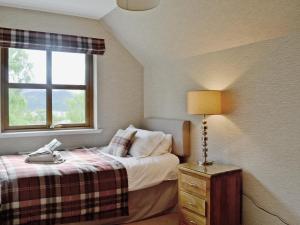 a bedroom with a bed with a lamp and a window at Lochnagar Lodge in Aviemore