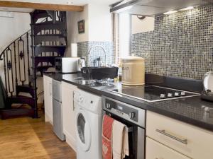 a kitchen with a sink and a washing machine at Marl Farm Cottage in Hayfield