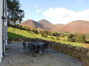 a patio with a table and chairs and mountains at Gutherscale Lodge in Portinscale