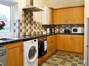 a kitchen with wooden cabinets and a washer and dryer at Doves Den in Gooseham