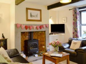 a living room with a fireplace and leather furniture at Park View Cottage in Old Glossop