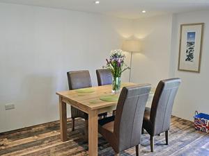 a dining room table with chairs and a vase of flowers on it at Grove Lodge - 27847 in Marazion
