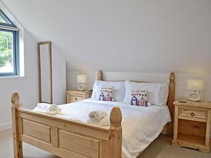 a bedroom with a wooden bed with two night stands at Grove Lodge - 27847 in Marazion