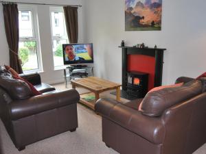 a living room with two leather couches and a fireplace at Badger Cottage in Ambleside