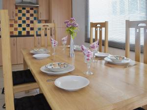 a wooden table with plates and glasses and flowers on it at The Coach House - Or4 in Henfynyw Upper