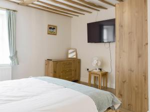 a bedroom with a bed and a flat screen tv at The Plough in Bampton