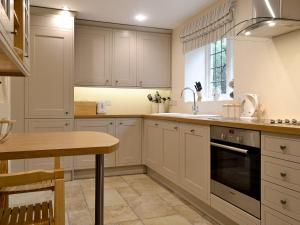 a kitchen with white cabinets and a sink and a stove at Old School House in Wyck Rissington