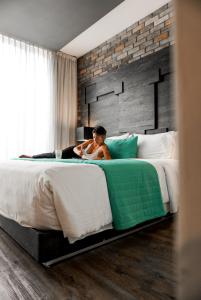 Hotel Punto MX في مدينة ميكسيكو: امرأة مستلقية على سرير في غرفة فندق