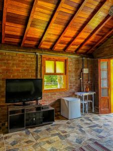 uma sala de estar com uma televisão de ecrã plano e uma mesa em Pousada - Casa de Barro em Santo Antônio do Pinhal