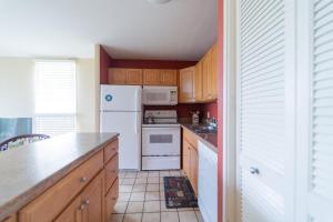 a kitchen with white appliances and wooden cabinets at 19th Hole Condo in Kahuku