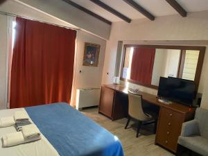 Habitación de hotel con cama, escritorio y TV. en Dionysion, en Thiva