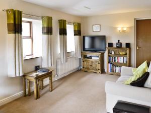 a living room with a couch and a tv at Greystones Cottage in Hardraw