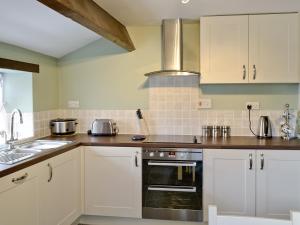 a kitchen with white cabinets and a sink at Greystones Cottage in Hardraw
