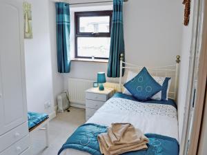 a bedroom with a bed with blue pillows and a window at Greystones Cottage in Hardraw