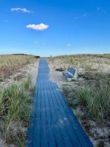 a wooden pathway leading to a bench on a beach at Sunshine House steps from Beach in Seabrook